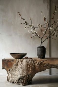 a wooden table topped with a vase filled with flowers next to a bowl on top of it