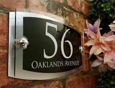 a close up of a sign on a brick wall with flowers in the foreground