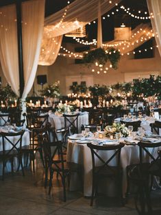 tables and chairs are set up with white tablecloths, candles and greenery