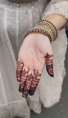 a woman's hand with henna tattoos and bracelets on it, showing her hands