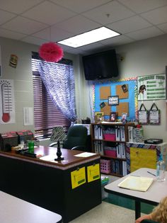 a classroom with desks, chairs and bookshelves in front of a window