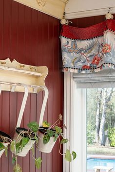 a potted plant hanging from a window sill in front of a red painted wall