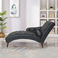 a black leather chaise lounger sitting in front of a book shelf filled with books