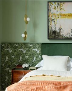 a bedroom with green walls and an orange bedspread on the bed is decorated with birds