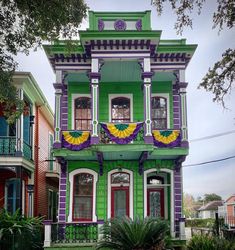 a green and purple house with lots of windows on the second floor is painted in bright colors