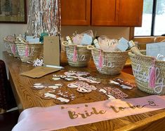 baskets filled with paper cutouts sitting on top of a wooden table next to a sign that says bride to be