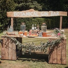 a wooden sign that says botanical gin bar on top of some crates with flowers around it