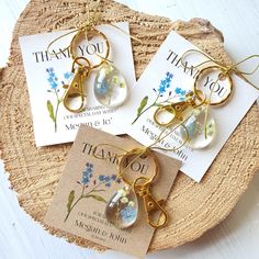 two thank you cards and some keychains on a piece of wood with flowers