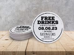 two white coasters sitting on top of a wooden table next to each other with free drinks printed on them