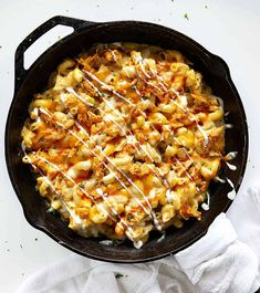 a skillet filled with macaroni and cheese on top of a white table