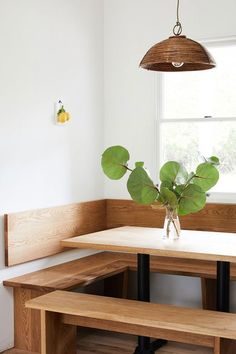 a wooden bench and table in a room with white walls, wood flooring and light fixture