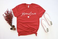 a red t - shirt with the word grandma on it next to some berries and sneakers