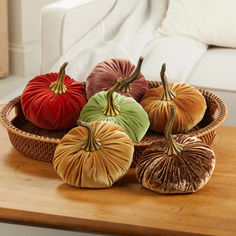 four decorative pumpkins in a basket on a table