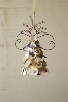 a christmas tree ornament hanging from a rope with shells on it's side