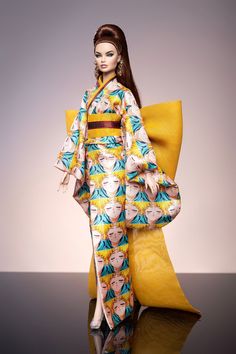 a woman in a kimono is standing on a black surface with a yellow pillow behind her