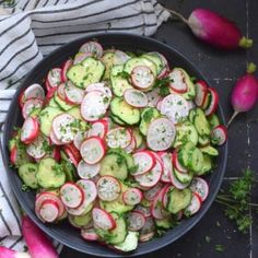 a bowl filled with cucumbers and radishes on top of a table