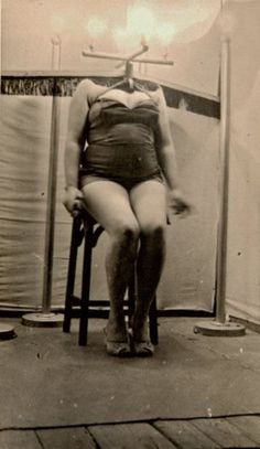 an old photo of a woman sitting on a chair in front of a shower stall