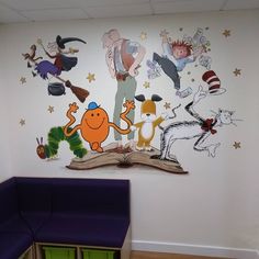 the children's room has an open book on the wall and many cartoon characters painted on it