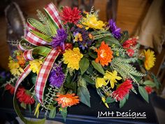 a bouquet of colorful flowers on top of a black table with red and white checkered ribbon