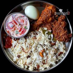 a silver plate topped with rice and meat next to an egg