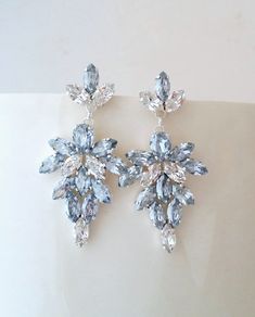 two pairs of blue and clear crystal earrings on top of a white surface with one pair missing