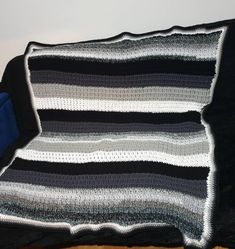 a black and white blanket sitting on top of a bed next to a blue pillow