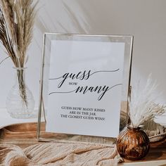 a sign that is on top of a wooden table next to a vase with dry grass in it