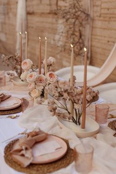 the table is set with candles, plates and napkins