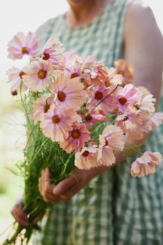 a woman holding a bunch of pink flowers