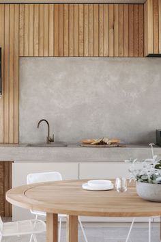 a kitchen with a wooden table and white chairs