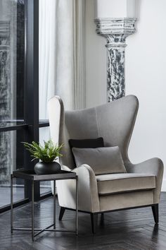 a chair and table in front of a window with a plant on top of it