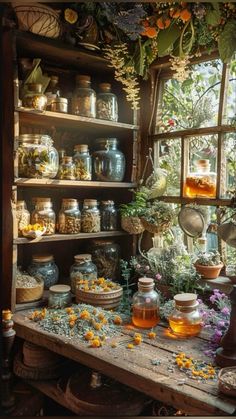 an old wooden table topped with lots of jars filled with flowers and plants next to a window