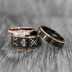 two wedding rings sitting on top of each other with diamonds in the middle and black bands around them