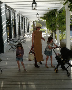 a woman and two children are standing on a porch