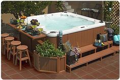 an outdoor hot tub surrounded by potted plants and bar stools on brick patio