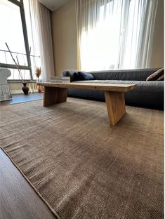 a living room area with a couch, coffee table and rug in front of a window