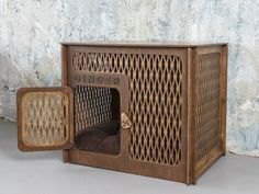 an old wooden box with a dog in it and the door open to another cage