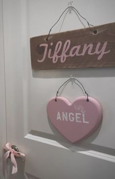 two wooden signs hanging from the side of a white door with pink ribbon on it