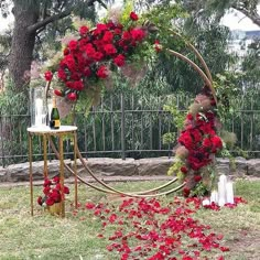 a table with red flowers on it and a wine bottle in the middle surrounded by petals