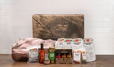 an assortment of food items sitting on top of a wooden table in front of a brick wall