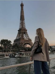 a woman standing in front of the eiffel tower looking out over the water