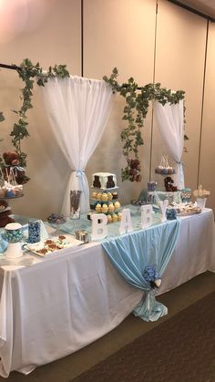 a table topped with lots of cakes and desserts covered in white draping