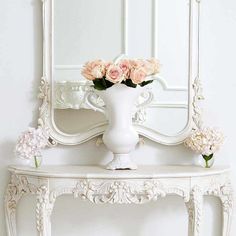 a white table with flowers and a mirror on it