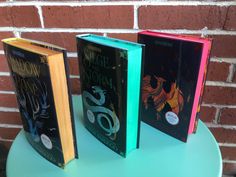 three books sitting on top of a table next to a brick wall