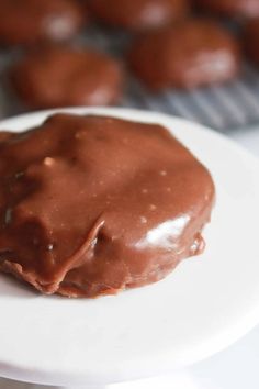 chocolate covered donuts on a white plate with cooling rack in the backgroud