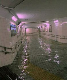 an empty swimming pool with tiled floors and railings on either side, surrounded by water