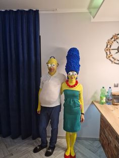 a man and woman dressed up as simpsons and the simpson are standing next to each other