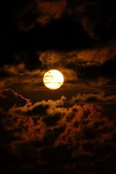 the full moon is shining brightly in the dark night sky with fluffy clouds around it