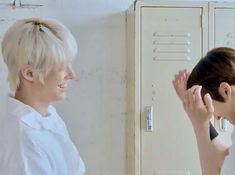 two women standing next to each other in front of lockers with their hands on their faces