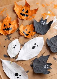 paper leaves with faces and bats on them are arranged in the shape of pumpkins